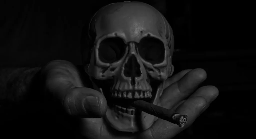 A skull with a cigar in its mouth, symbolizing lust even after death