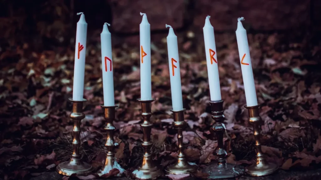 6 white candles in golden candlesticks with the runic text 'FUTHARK' inscribed on them