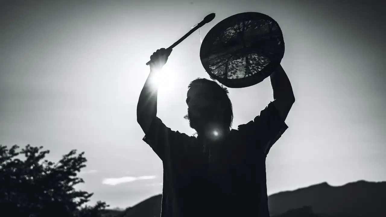 Modern shamanic practitioner holding a shamanic drum above his head